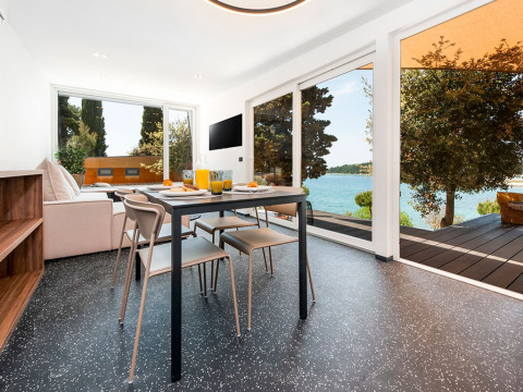 Moderne eetruimte met zicht op het meer en bomen bij Family Holiday Home Pool, Camping Porton Nature Hideouts, Kroatië.