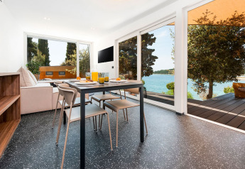 Comedor moderno con vistas al lago y árboles en Family Holiday Home Pool, Camping Porton Nature Hideouts, Croacia.