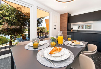 Cucina moderna e zona pranzo con vista sulla terrazza e sulla natura al Family Holiday Home Pool – 2 moduli al Camping Porton Nature Hideouts, Croazia.