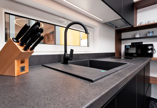 Fregadero moderno con grifo negro, bloque de cuchillos y microondas en Family Holiday Home Pool, Porton Nature, Croacia.