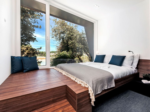 Moderne slaapkamer met groot panoramavenster, houten accenten en uitzicht op de natuur in Camping Porton, Kroatië.