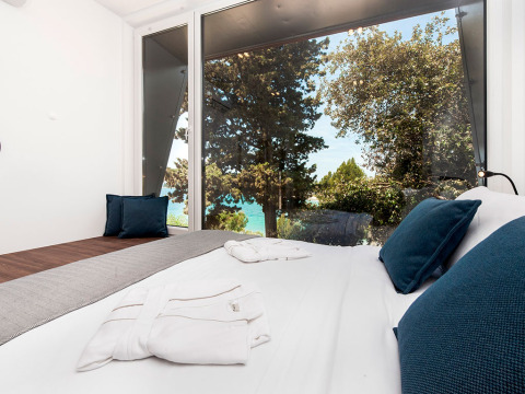 Moderne slaapkamer in Family Holiday Home Pool in Kroatië met grote ramen, zeezicht en bomen buiten.