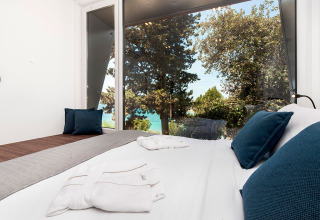 Moderne slaapkamer in Family Holiday Home Pool in Kroatië met grote ramen, zeezicht en bomen buiten.
