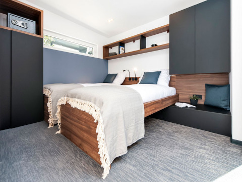 Moderne slaapkamer met houten bedden, blauwe en witte accenten en minimalistische inrichting in Kroatië.