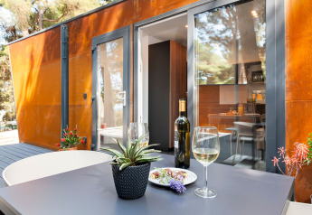 Moderne terras met wijnfles en glas aan Couple Holiday Home Pool bij Camping Porton Nature Hideouts, Kroatië.