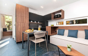 Modern lodge interior with dining table, sofa, cushions, and large window at Couple Holiday Home Pool Croatia.