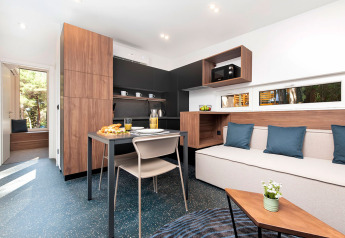 Interno moderno di lodge con tavolo, divano, cuscini e ampia finestra al Couple Holiday Home Pool Croazia.