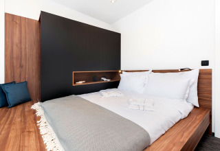 Modernes Schlafzimmer mit Doppelbett und Holzmöbeln im Couple Holiday Home Pool bei Camping Porton Nature Hideouts.