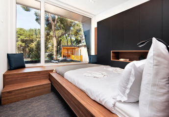 Dormitorio moderno con muebles de madera y gran ventana en Couple Holiday Home Pool, Camping Porton Nature Hideouts.