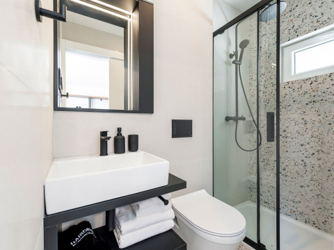 Bagno moderno con doccia in vetro, specchio illuminato e lavandino al Family Holiday Home Pool, Camping Porton, Croazia.