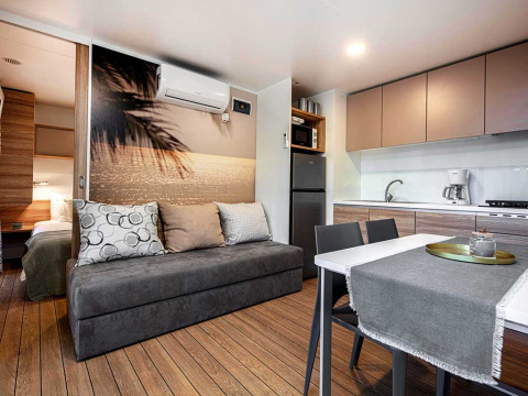 Modern lodge-interieur bij Porton op Camping Porton Nature Hideouts in Kroatië met keuken en bank.