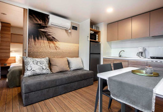 Modern lodge-interieur bij Porton op Camping Porton Nature Hideouts in Kroatië met keuken en bank.