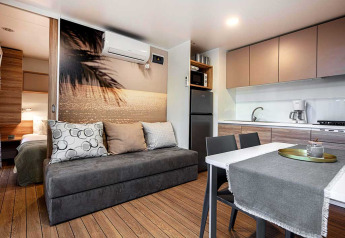 Modern lodge interior at Porton in Camping Porton Nature Hideouts, Croatia, featuring kitchen and sofa.