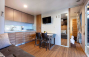 Modern lodge at Camping Porton Nature Hideouts in Croatia featuring kitchen, dining table and sofa area.