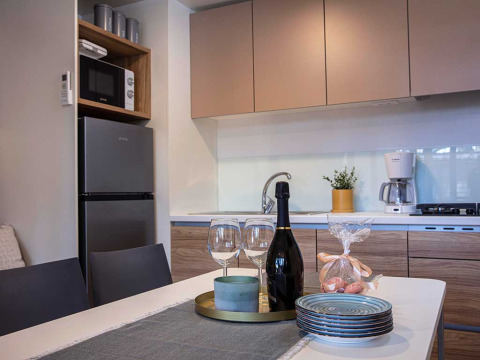 Moderne kitchenette in Porton lodge bij Camping Porton Nature Hideouts in Kroatië met servies op tafel.