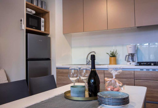 Moderne kitchenette in Porton lodge bij Camping Porton Nature Hideouts in Kroatië met servies op tafel.