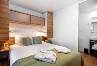 Moderne slaapkamer in een Porton-lodge bij Camping Porton Nature Hideouts, Kroatië, met tweepersoonsbed.