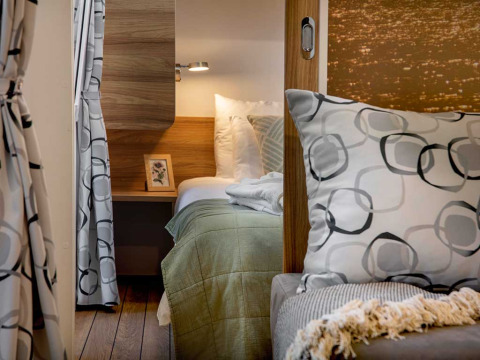 Gezellige slaapkamer met modern interieur, groen beddengoed en kussens bij Camping Porton Nature Hideouts in Kroatië.