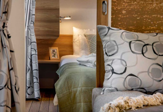 Gezellige slaapkamer met modern interieur, groen beddengoed en kussens bij Camping Porton Nature Hideouts in Kroatië.