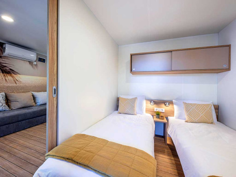 Moderne lodge slaapkamer met twee eenpersoonsbedden en aangrenzende lounge bij Camping Porton, Kroatië.