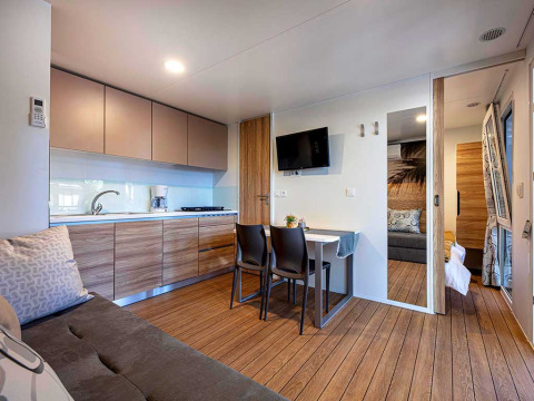 Modern lodge-interieur met keuken, eethoek, bank en slaapkamer bij Camping Porton Nature Hideouts, Kroatië.