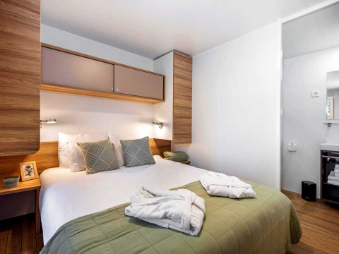 Modernes Schlafzimmer im Porton Pool, Camping Porton Nature Hideouts, Kroatien, mit Doppelbett und Bad.