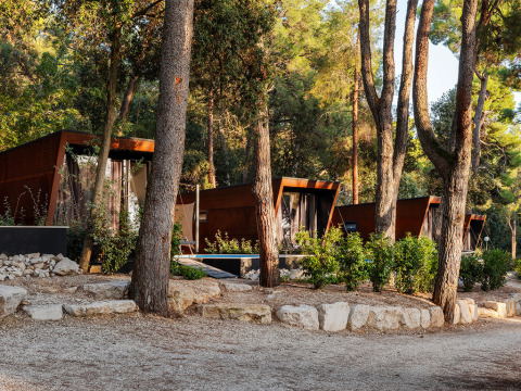 Moderne lodges bij Porton Pool op Camping Porton Nature Hideouts, gelegen tussen de bomen in Kroatië.