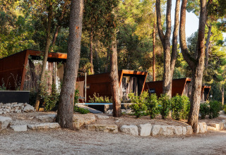 Moderne Lodges am Porton Pool bei Camping Porton Nature Hideouts, umgeben von Wald in Kroatien.