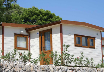 Baia Lux lodge bij Baia Holiday Poljana in Kroatië, wit chalet met houtafwerking en stenen muurtje vooraan.