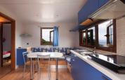 Cucina e zona pranzo moderne con mobili blu e vista mare al Baia Lux, Baia Holiday Poljana, Croazia.
