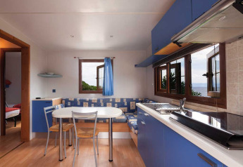 Cucina e zona pranzo moderne con mobili blu e vista mare al Baia Lux, Baia Holiday Poljana, Croazia.