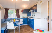 Cucina e zona pranzo moderne con mobili blu e divano angolare nella Baia Superior al Baia Holiday Poljana.