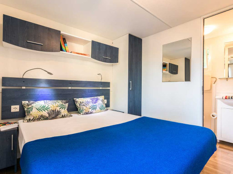 Chambre moderne avec lit double, couverture bleue, placards et miroir au Baia Superior, Poljana, Croatie.