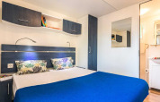 Camera moderna con letto matrimoniale, coperta blu, armadi e specchio al Baia Superior, Poljana, Croazia.