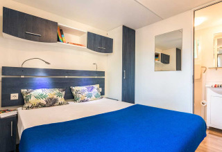 Chambre moderne avec lit double, couverture bleue, placards et miroir au Baia Superior, Poljana, Croatie.