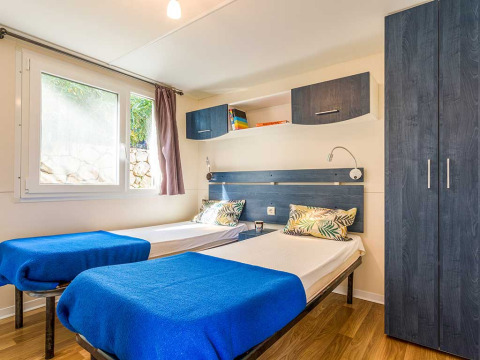 Deux lits simples avec des couvertures bleues dans une chambre lumineuse de Baia Superior, Baia Holiday Poljana, Croatie.