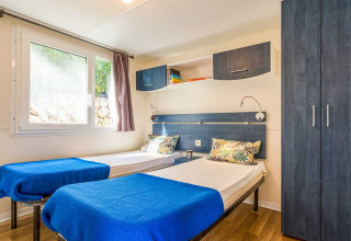 Deux lits simples avec des couvertures bleues dans une chambre lumineuse de Baia Superior, Baia Holiday Poljana, Croatie.