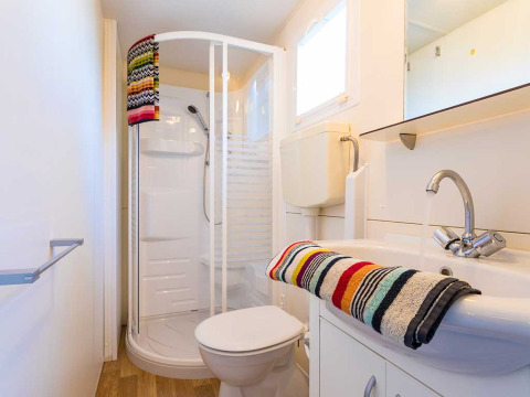 Salle de bain moderne dans un lodge à Baia Holiday Poljana en Croatie, avec douche et serviettes colorées.