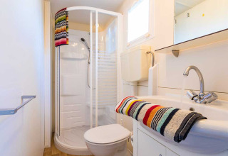 Salle de bain moderne dans un lodge à Baia Holiday Poljana en Croatie, avec douche et serviettes colorées.