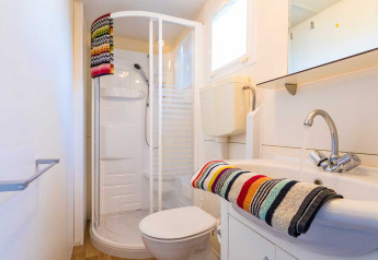 Salle de bain moderne dans un lodge à Baia Holiday Poljana en Croatie, avec douche et serviettes colorées.