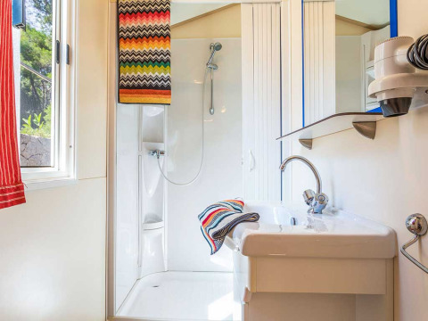 Salle de bain moderne avec douche, lavabo et serviettes colorées au Blu Romantic, Baia Holiday Poljana, Croatie.