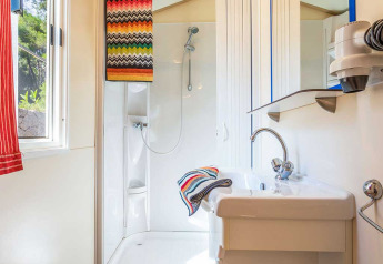Salle de bain moderne avec douche, lavabo et serviettes colorées au Blu Romantic, Baia Holiday Poljana, Croatie.