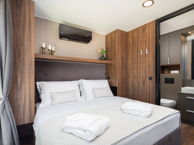 Camera moderna con letto matrimoniale, arredo in legno e bagno privato in chalet di lusso in Croazia.