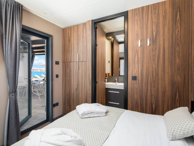 Camera da letto con pannelli in legno, accesso alla terrazza e vista mare ad Avalona Luxury Mare Glamping Villa in Croazia.