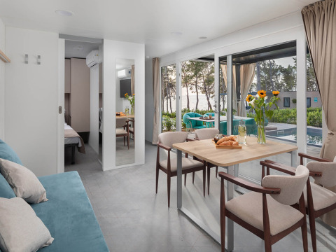 Modernes Ferienhaus mit Essbereich, Sofa und großen Fenstern mit Blick auf Pool und Meer in Kroatien.