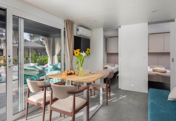 Helles, modernes Ferienhaus mit Essbereich, Blumen und Blick auf die Terrasse im Aminess Style Camping Avalona Resort, Kroatien.
