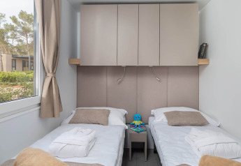 Modernes Schlafzimmer mit zwei Einzelbetten, Schränken und Fenster in Aminess Style Camping Avalona Resort, Kroatien.