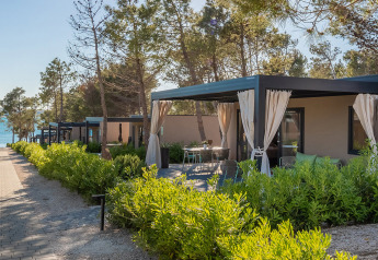 Chalet Premium Holiday Home con terrazza privata e tende, immerso nel verde vicino al mare.