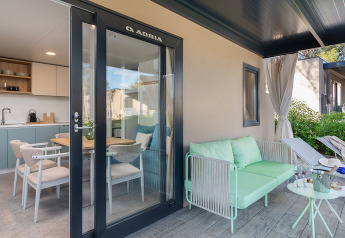 Terrazza esterna con divano e tavolo davanti a una cucina moderna al Premium Holiday Home, Aminess Style Camping Avalona Resort, Croazia.