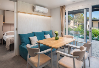 Soggiorno moderno con tavolo da pranzo e divano blu nel Premium Holiday Home di Aminess Style Camping Avalona Resort, Croazia.